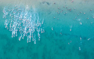 A photo of a bright blue ocean, with a huge number of triathletes swimming in it